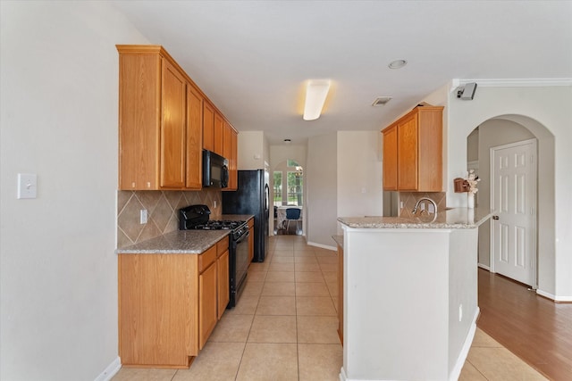 kitchen featuring black appliances, decorative backsplash, light stone countertops, and light tile patterned floors