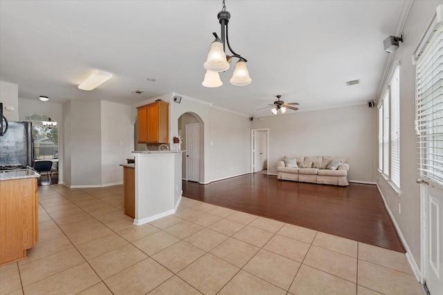 kitchen featuring ceiling fan with notable chandelier, refrigerator, crown molding, decorative light fixtures, and light tile patterned flooring