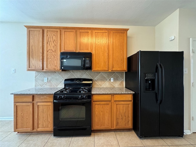 kitchen featuring light tile patterned floors, tasteful backsplash, light stone counters, and black appliances