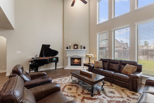 living room with ceiling fan, a towering ceiling, and hardwood / wood-style flooring