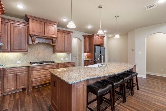 kitchen with hanging light fixtures, an island with sink, and stainless steel appliances