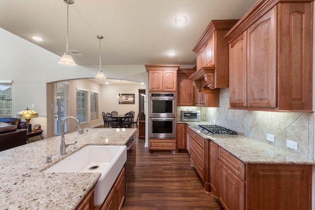 kitchen featuring pendant lighting, sink, decorative backsplash, light stone countertops, and stainless steel appliances