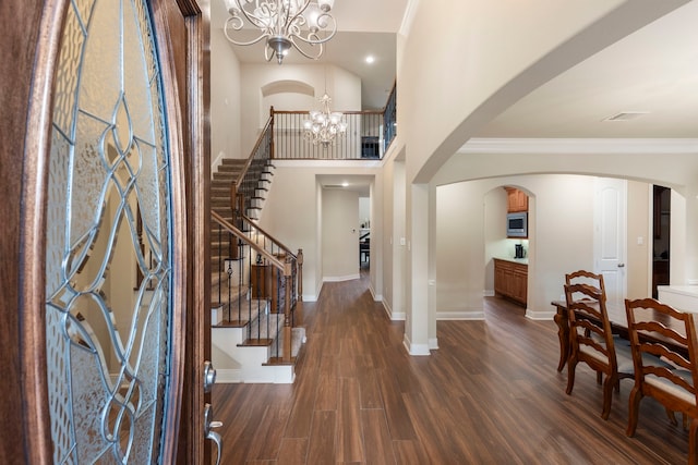 entrance foyer featuring a towering ceiling, dark hardwood / wood-style floors, crown molding, and a notable chandelier