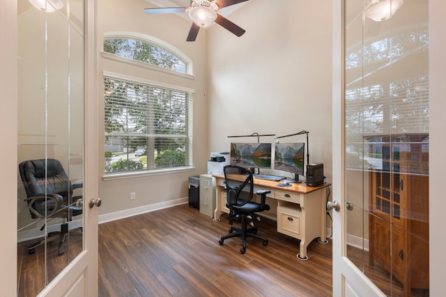 home office with dark hardwood / wood-style floors, ceiling fan, and french doors