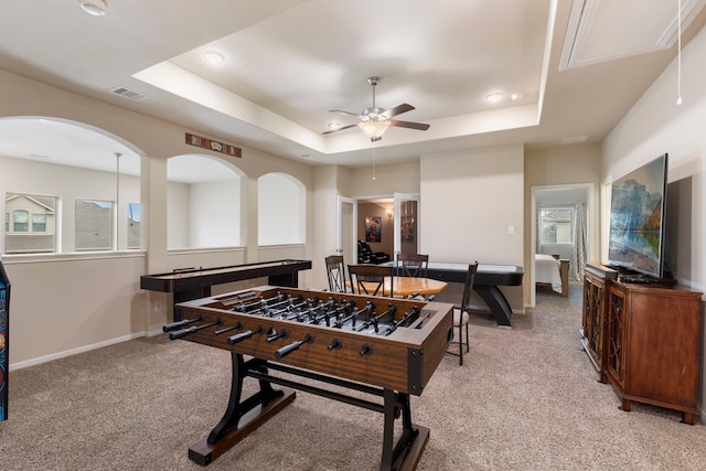 playroom featuring ceiling fan, a raised ceiling, and light carpet