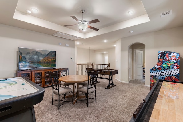 recreation room with a raised ceiling, ceiling fan, and carpet