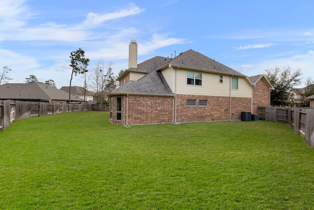 rear view of property with central AC and a lawn