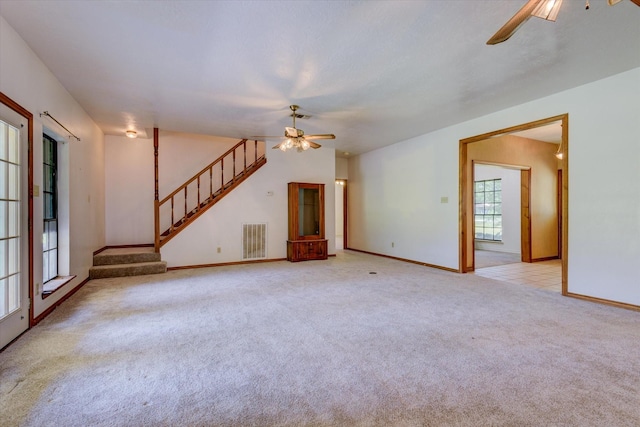 unfurnished living room with light colored carpet and ceiling fan