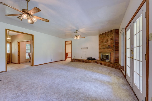 unfurnished living room with ceiling fan, a fireplace, light carpet, and french doors