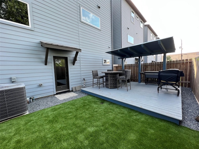 rear view of property featuring a yard, cooling unit, and a deck