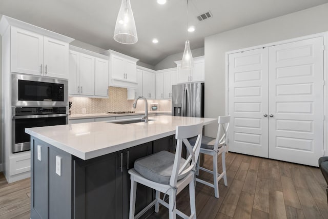 kitchen featuring a kitchen island with sink, sink, white cabinets, and stainless steel appliances