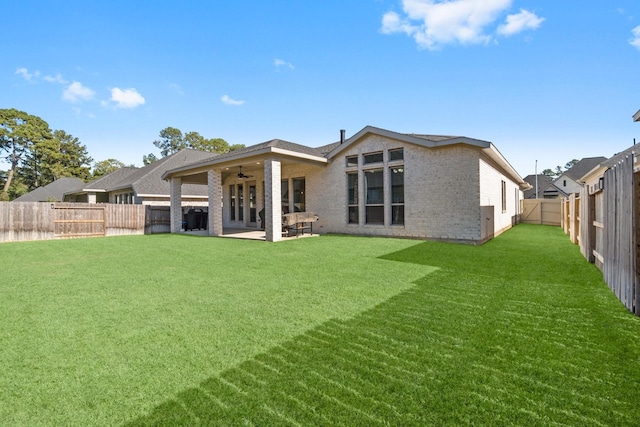 rear view of house with a patio, ceiling fan, and a lawn