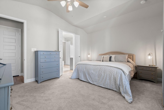 carpeted bedroom with ceiling fan, ensuite bathroom, and vaulted ceiling