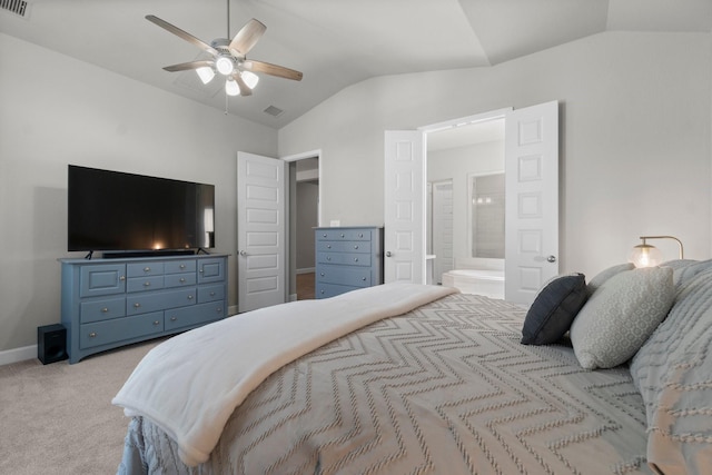 bedroom with ceiling fan, light colored carpet, lofted ceiling, and ensuite bath