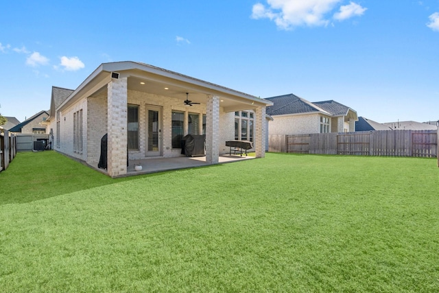 rear view of house featuring central AC unit, ceiling fan, a patio area, and a yard