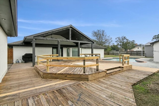 wooden deck featuring a fenced in pool and a grill