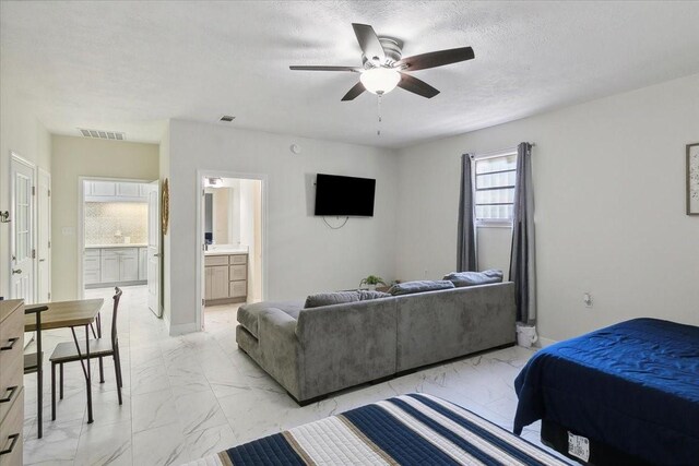 bedroom featuring ceiling fan, ensuite bathroom, and a textured ceiling