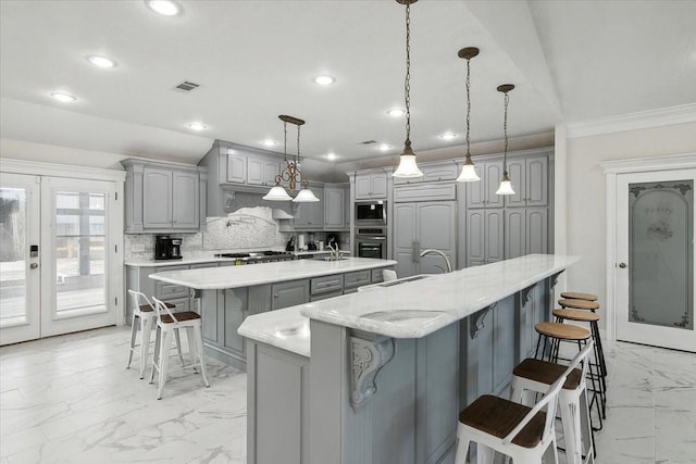 kitchen featuring backsplash, pendant lighting, a spacious island, gray cabinets, and appliances with stainless steel finishes