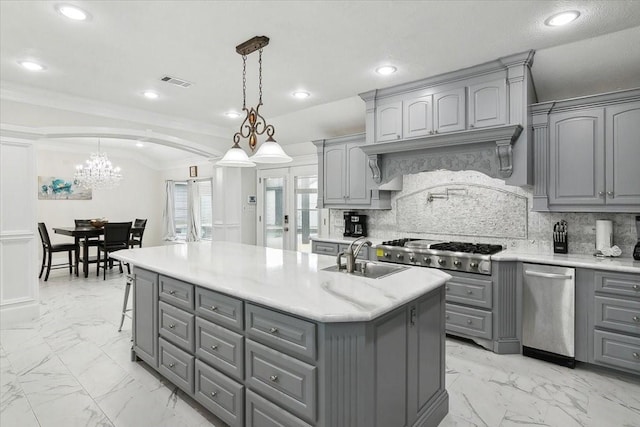 kitchen featuring decorative light fixtures, gray cabinets, sink, and an island with sink