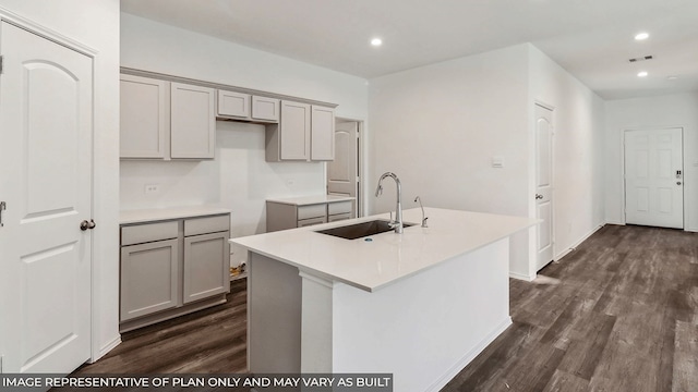 kitchen with dark hardwood / wood-style floors, a kitchen island with sink, and gray cabinetry