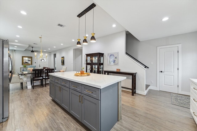 kitchen with a center island, stainless steel fridge, pendant lighting, gray cabinets, and light wood-type flooring