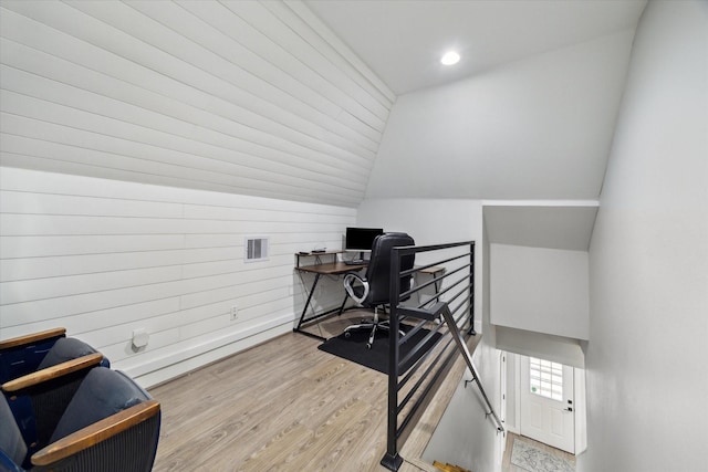 office featuring lofted ceiling, wooden walls, and light hardwood / wood-style flooring