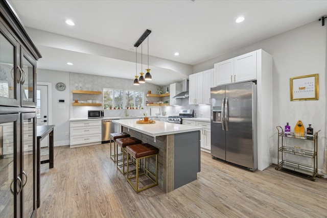 kitchen featuring stainless steel appliances, white cabinetry, a kitchen island, and light hardwood / wood-style flooring