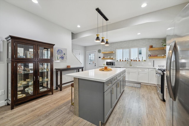 kitchen featuring appliances with stainless steel finishes, light wood-type flooring, gray cabinetry, pendant lighting, and white cabinetry