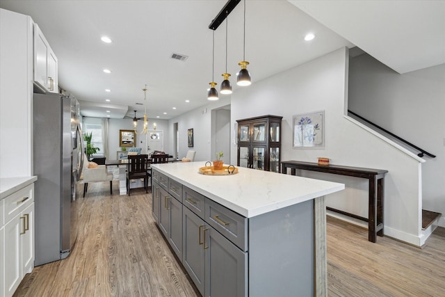 kitchen featuring white cabinetry, stainless steel fridge, pendant lighting, and light wood-type flooring