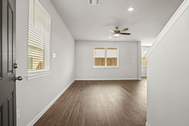 unfurnished living room with dark wood-style flooring, a wealth of natural light, and baseboards