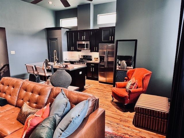 living room with sink, light hardwood / wood-style floors, and ceiling fan