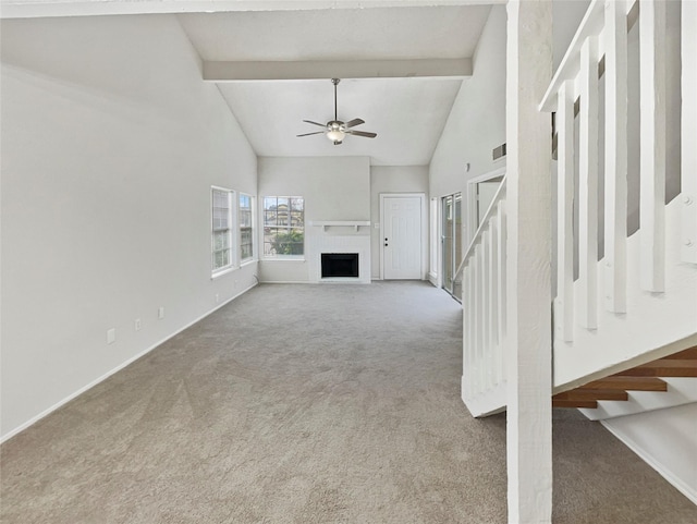 unfurnished living room with ceiling fan, a brick fireplace, beamed ceiling, high vaulted ceiling, and carpet floors