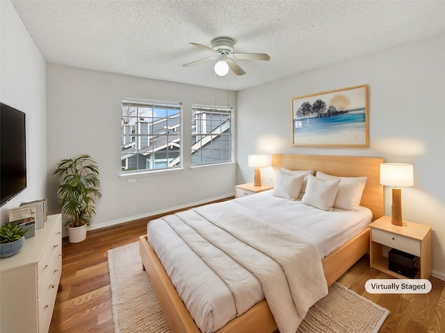 bedroom with a textured ceiling, light wood-type flooring, and ceiling fan