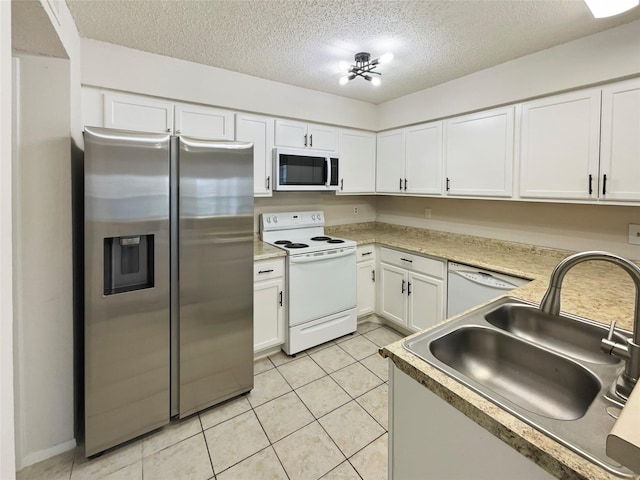 kitchen with white appliances, sink, light tile patterned floors, a textured ceiling, and white cabinetry