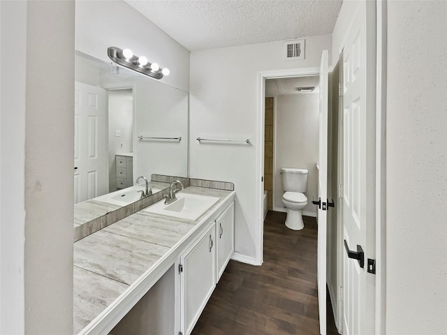 bathroom with vanity, a textured ceiling, hardwood / wood-style flooring, and toilet