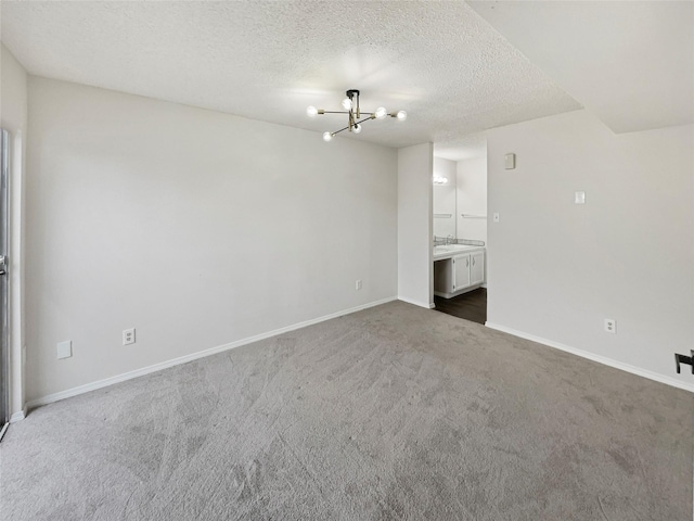 interior space with dark colored carpet, a textured ceiling, and a notable chandelier