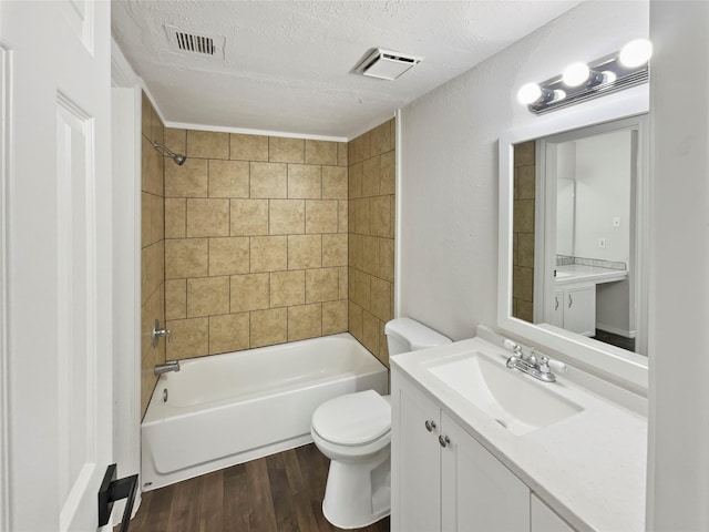 full bathroom with tiled shower / bath combo, wood-type flooring, a textured ceiling, toilet, and vanity