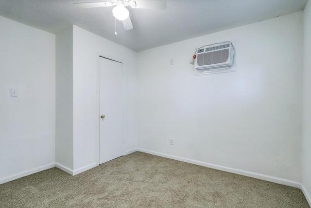 unfurnished room with a wall mounted AC, ceiling fan, light colored carpet, and a textured ceiling