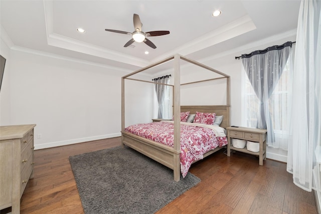 bedroom featuring dark hardwood / wood-style flooring, a tray ceiling, ceiling fan, and crown molding