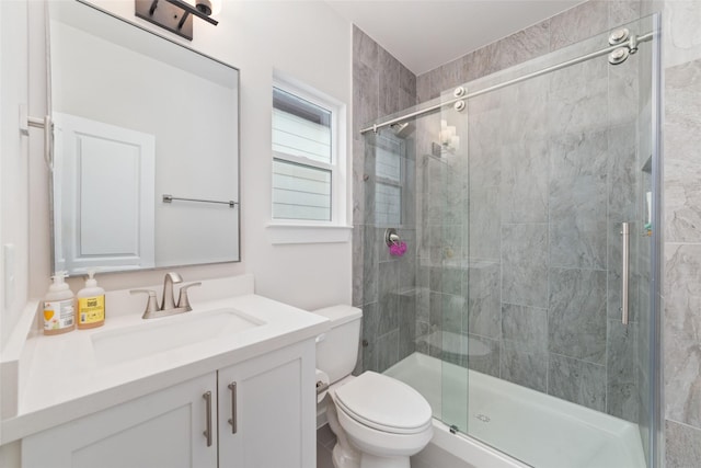 bathroom featuring vanity, toilet, and a shower with door