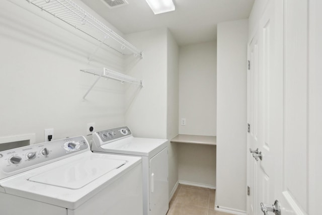 washroom featuring light tile patterned floors, laundry area, visible vents, baseboards, and washing machine and clothes dryer