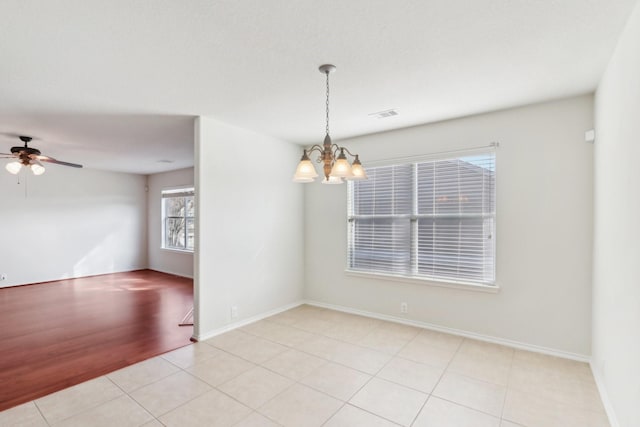 unfurnished room featuring ceiling fan with notable chandelier, light tile patterned flooring, visible vents, and baseboards