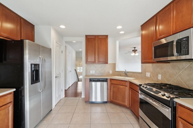 kitchen with brown cabinets, appliances with stainless steel finishes, light countertops, and a sink