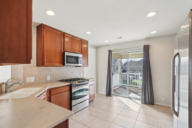 kitchen with stainless steel appliances, a sink, visible vents, light countertops, and decorative backsplash