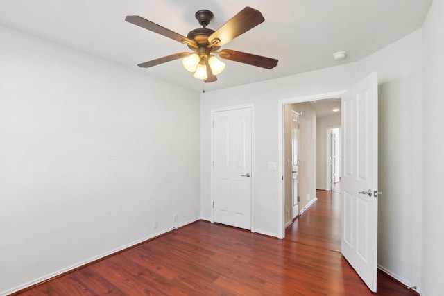 unfurnished bedroom featuring dark wood-type flooring, a ceiling fan, and baseboards