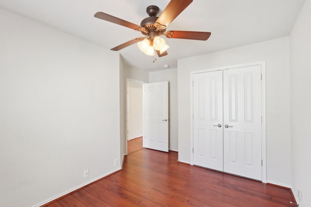 unfurnished bedroom with ceiling fan, a closet, baseboards, and dark wood-style flooring