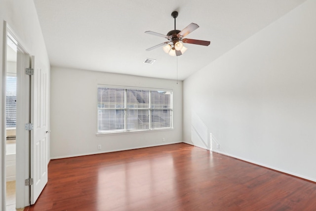 empty room featuring lofted ceiling, dark wood-style flooring, ceiling fan, and baseboards