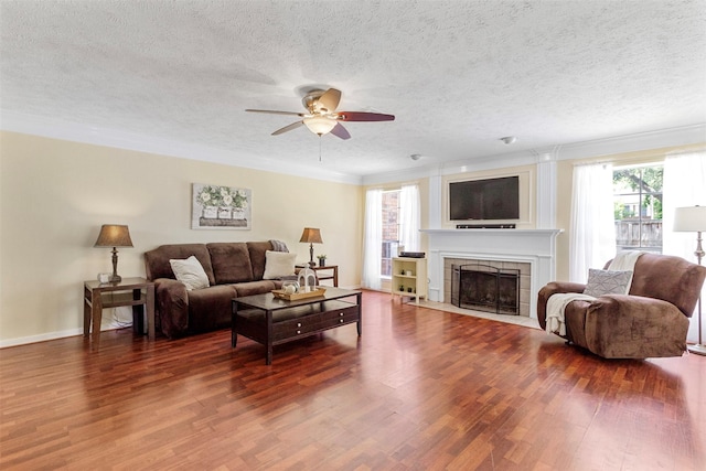 living room with a textured ceiling, ceiling fan, dark wood-type flooring, and a tiled fireplace