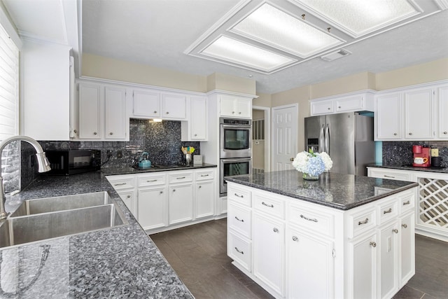 kitchen with white cabinetry, sink, dark stone countertops, a kitchen island, and black appliances