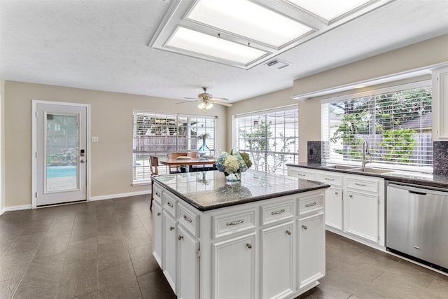 kitchen with ceiling fan, dishwasher, sink, a kitchen island, and white cabinets